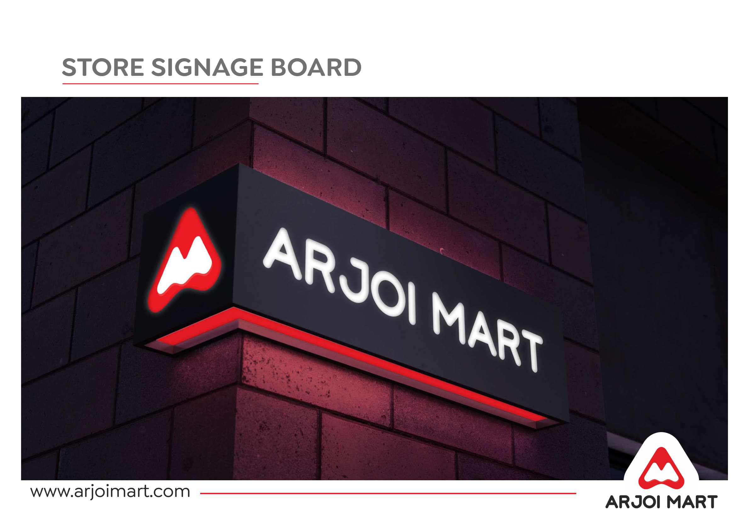 Store signage board — illuminated Arjoi Mart corner sign on dark brick wall